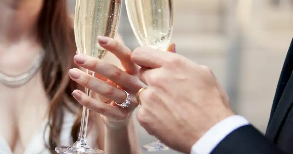 Hendene til et nygift par som skåler i champagne